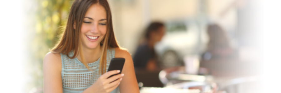 Woman sitting at table smiling at her cell phone